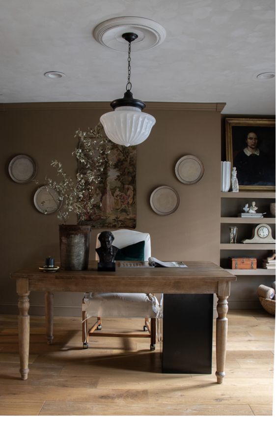 a sophisticated taupe home office with open shelves, a vintage desk, a white chair, some decor and a pendant lamp