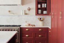 a sophisticated vintage red kitchen with shaker cabinets, a white backsplash and countertops and a large hood
