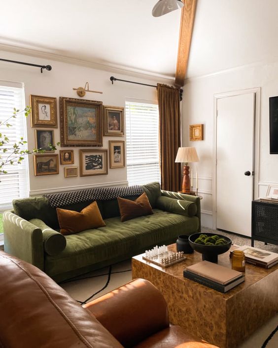 a stylish and refined living room with a green some, a brown chair, a stone coffee table, a gallery wall and some lamps
