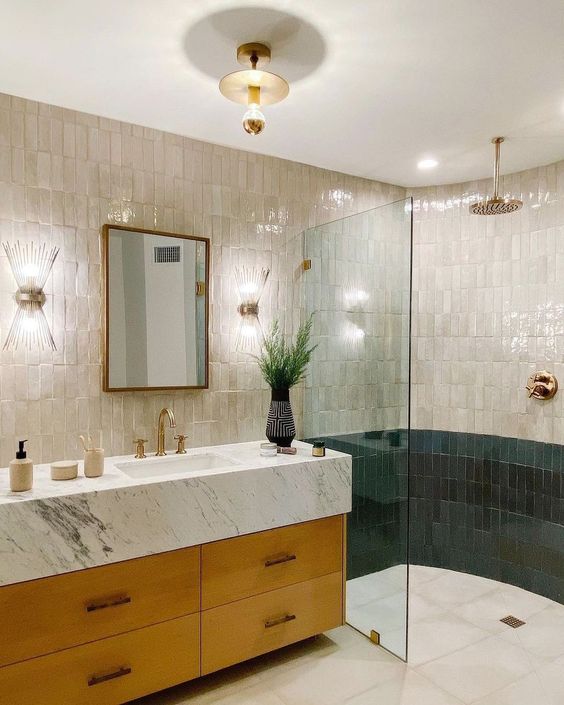 a stylish bathroom with a curved shower wall, stacked neutral and grene Zellige tiles and a stained vanity is glam