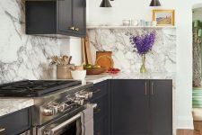 a stylish graphite grey kitchen with white stone countertops and a backsplash, a gold hood for an accent is wow