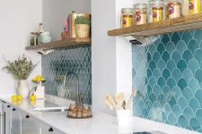 a stylish modern white kitchen with an eye-catchy blue and turquoise scallop tile backsplash and open shelves