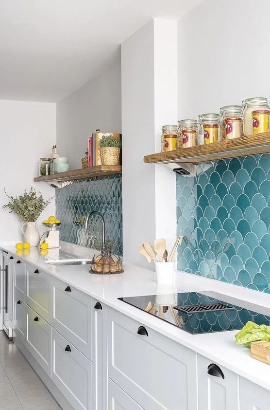 A stylish modern white kitchen with an eye catchy blue and turquoise scallop tile backsplash and open shelves