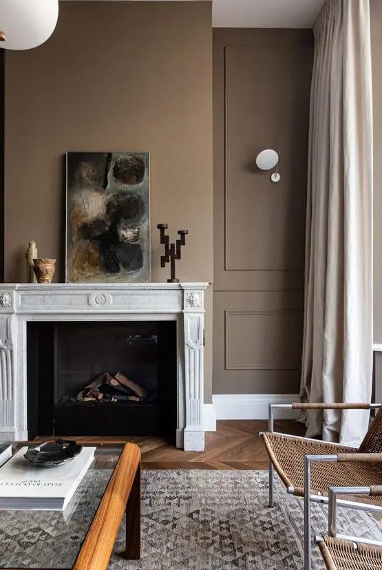 a subtle living room with light brown walls, a refined fireplace, a glass coffee table and woven chairs