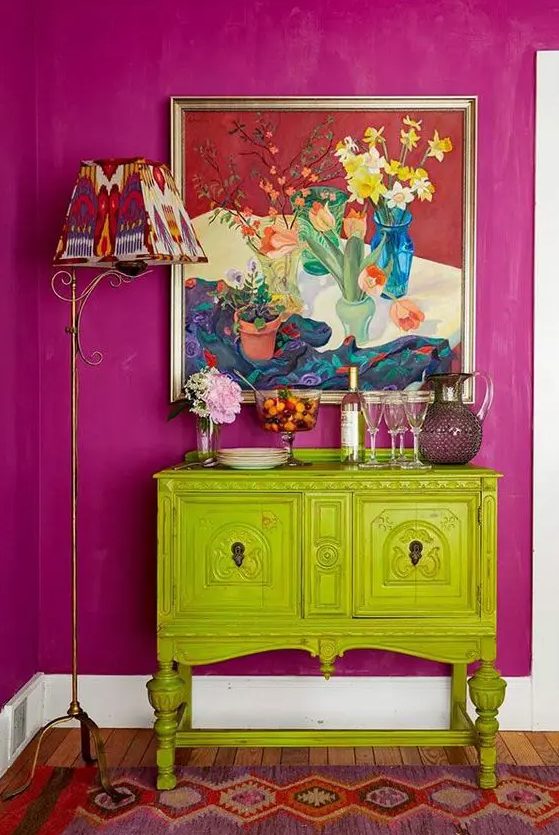 a super bold combo of a fuchsia wall and a chartreuse vintage cabinet, a bold artwork and a floor lamp
