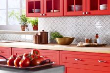 a super bold hot red kitchen with glass cabinets and shaker ones, a printed tile backsplash and butcherblock countertops