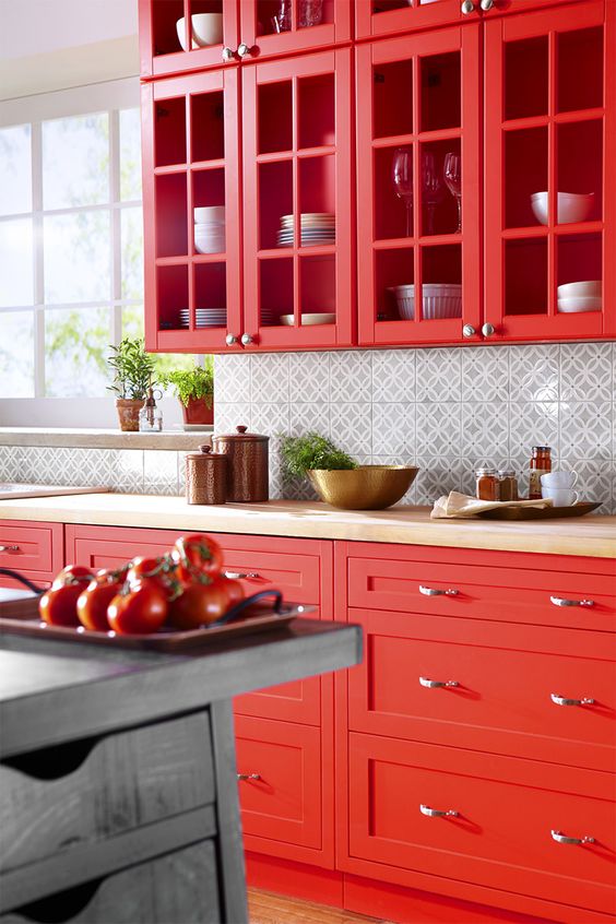 a super bold hot red kitchen with glass cabinets and shaker ones, a printed tile backsplash and butcherblock countertops