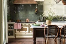 a vintage creamy kitchen with a green Zellige tile backsplash, a copper hood and an elegant and chic kitchen island