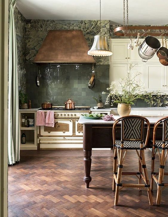 a vintage creamy kitchen with a green Zellige tile backsplash, a copper hood and an elegant and chic kitchen island