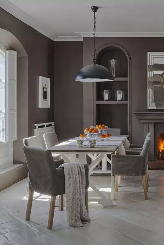 a vintage-inspired taupe dining room with a window in an alcove, built-in shelves, a fireplace, a trestle dining table and grey chairs