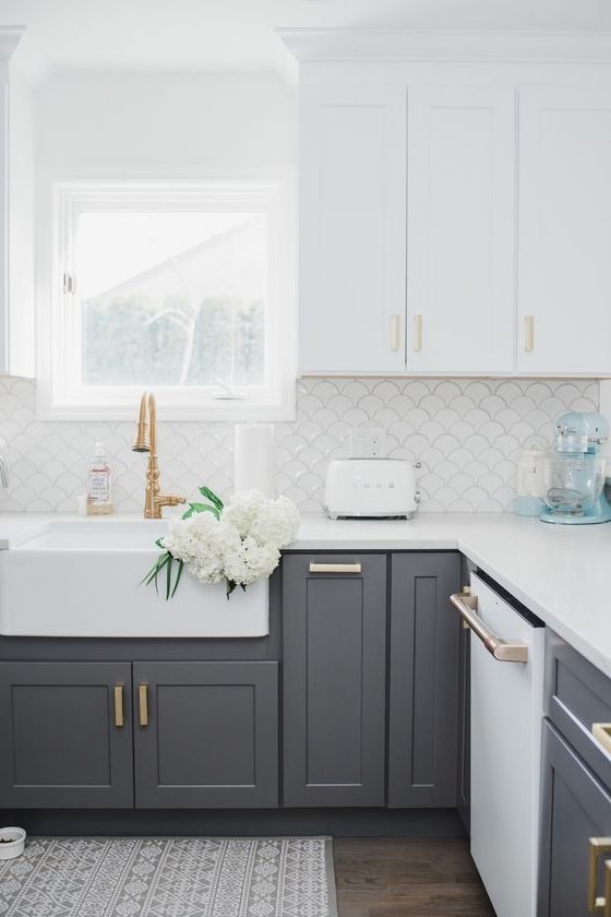 a white and grey kitchen with shaker cabinets, copper fixtures and a scallop tile backsplash is a lovely and chic space