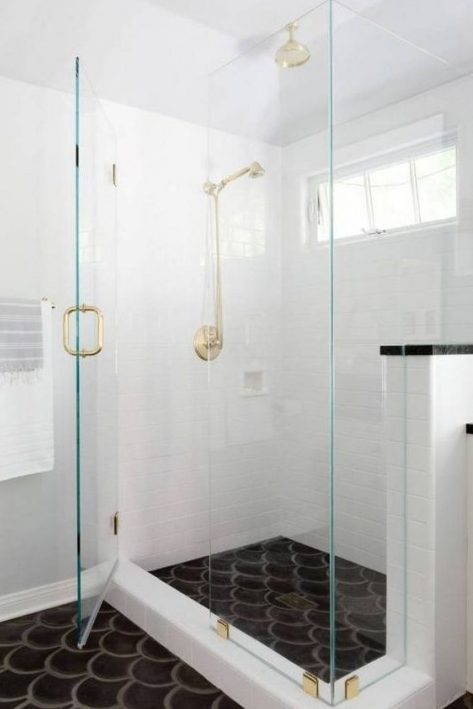 a white bathroom and a black fishscale tile floor for a bold monochromatic look accented with gold and brass