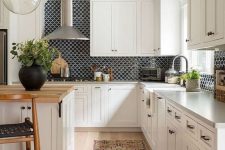 a white farmhouse kitchen with shaker cabinets, a kitchen island with a butcherblock countertop, a black scallop tile backsplash and a boho rug