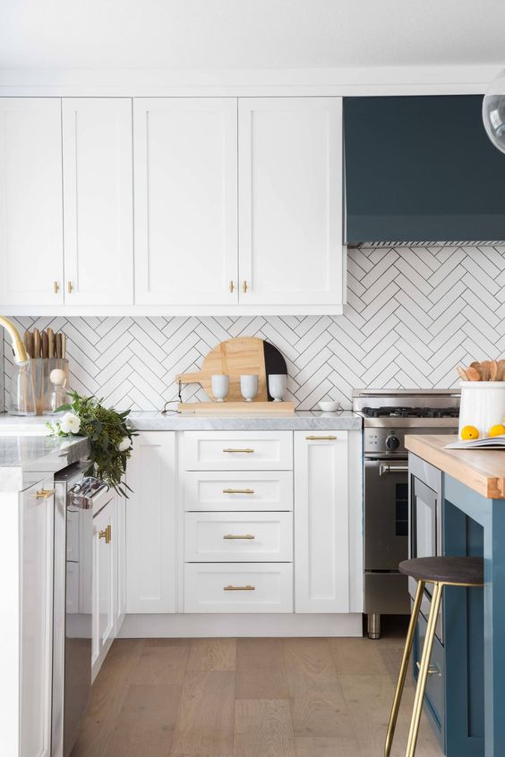 a white farmhouse kitchen with shaker cabinets, a navy kitchen island, stone and butcherblock countertops