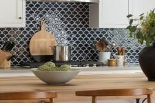 a white farmhouse kitchen with shaker cabinets, butcherblock countertops, a black fishscale tile backsplash and stools
