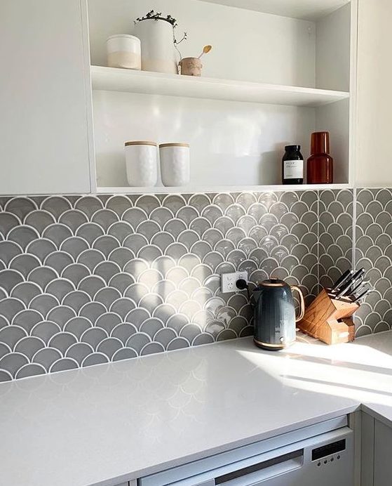 a white kitchen with a grey fish scale tile backsplash that adds color and texture to the space