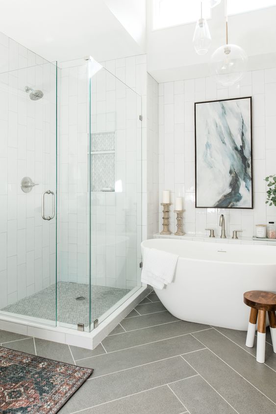 an airy bathroom with white skinny tiles and large scale herringbone ones, a skylight, a shower and a tub plus some decor