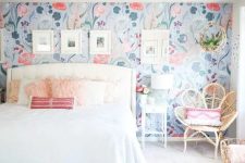 an airy bedroom with a bright floral accent wall, a white bed with neutral bedding, a blue boho rug, a rattan chair and white nightstands