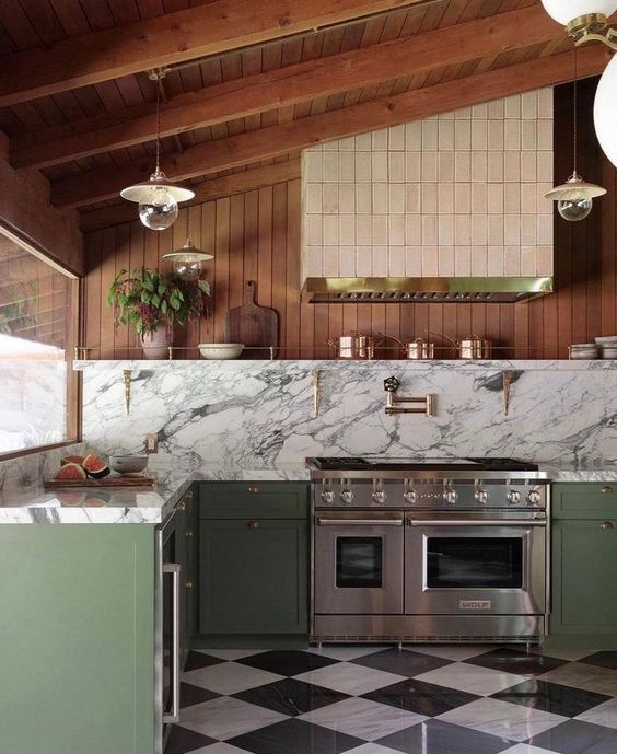 an attic kitchen with green lower cabinets, an open shelf, a large cooker and a large tiled hood plus some greenery