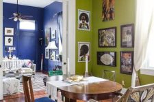 an eclectic dining room with chartreuse walls, a stained table, mismatching chairs, a crystal chandelier and a corner gallery wall