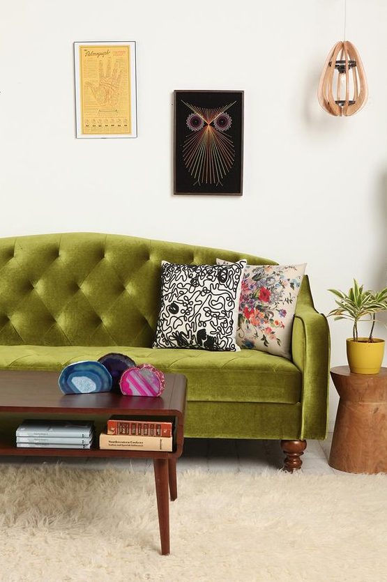 an eclectic living room with a chartreuse tufted sofa, a stained coffee table, a gallery wall and a pendant lamp