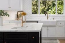 an elegant and refined kitchen with white shaker cabinets, a black kitchen island, white stone countertops and a white chevron tile backsplash