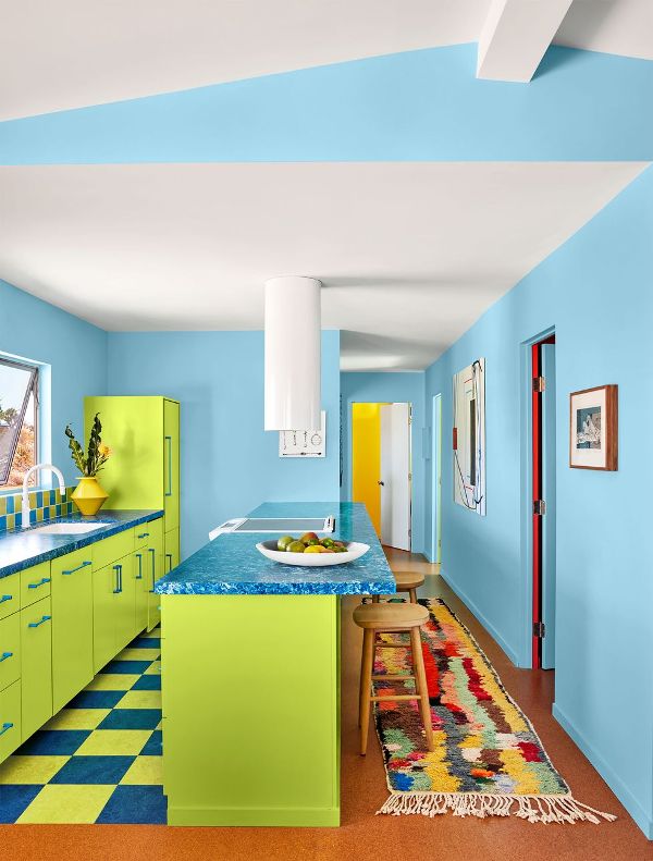 an extra bold kitchen with blue walls, chartreuse cabinets, a checked floor and a bold rug plus some decor