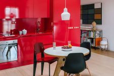 an extra bold red kitchen with matching countertops and a backsplash, a white round table and mismatching chairs