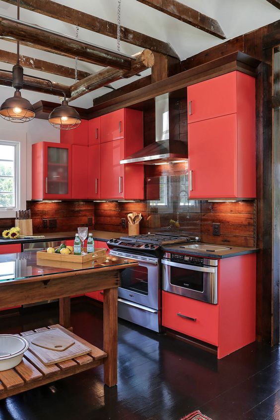 An extra bold red kitchen with stainless steel appliances, built in lights and metal pendant lamps is a cool space