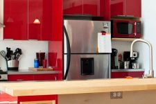 an extra bright red kitchen with glossy panels, a red and stained kitchen island, grey countertops