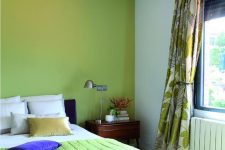 an eye-catchy bedroom with a chartreuse accent wall and a blanket, a bed with neutral bedding, printed curtains