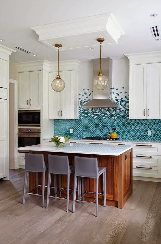 An eye catchy kitchen with creamy shaker cabinets, a bold turquoise and green scallop tile backsplash, a stained kitchen island and taupe stools