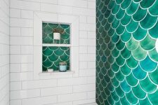 an eye-catchy shower space done with marble subway and green fishscale tiles, a niche shelf is a cool and bold idea
