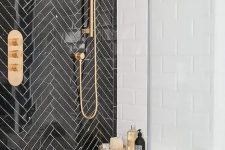 black herringbone tiles with white grout for accentuating the shower space and brass touches for a chic look