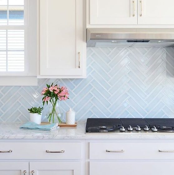 light blue skinny tiles done in a chevron pattern add both pattern and color to the space and make it catchier
