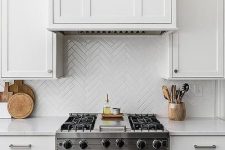 white skinny tiles clad in a herringbone pattern match the cabinets and add pattern interest to the kitchen