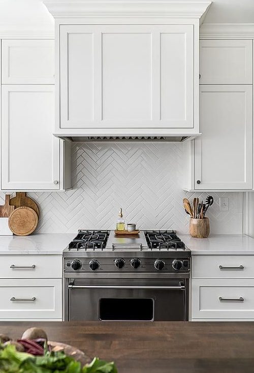 white skinny tiles clad in a herringbone pattern match the cabinets and add pattern interest to the kitchen