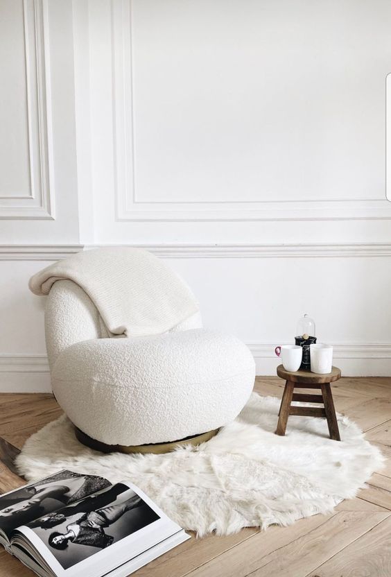 a beautiful curved white boucle chair, a stained side table, a faux fur rug are a cool and trendy combo for a living room