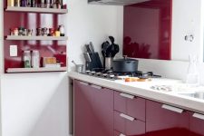 a beautiful deep burgundy contemporary kitchen with a white countertop and a backsplash, a burgundy backsplash and a shelving unit