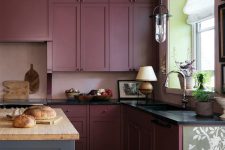 a beautiful deep burgundy kitchen with black countertops and a grey kitchen island plus a butcherblock countertop