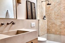 a beautiful earthy bathroom with a large shower space done with terracotta tile, a skylight, a vanity and a pink concrete sink