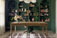 a beautiful home office with dark green built-in bookcases using IKEA Billy shelves, a stained desk and a chair plus a flower chandelier