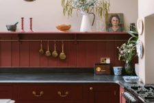 a beautiful vintage burgundy kitchen with black countertops and an open shelf, some decor and blooms is amazing