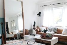 a boho living room with a leather sofa, a low coffee table, an oversized mirror in a simple wooden frame is very welcoming
