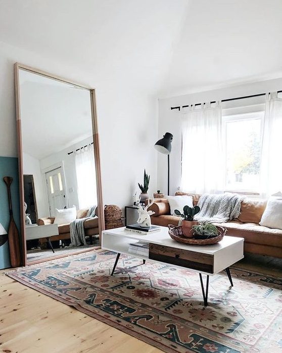 a boho living room with a leather sofa, a low coffee table, an oversized mirror in a simple wooden frame is very welcoming