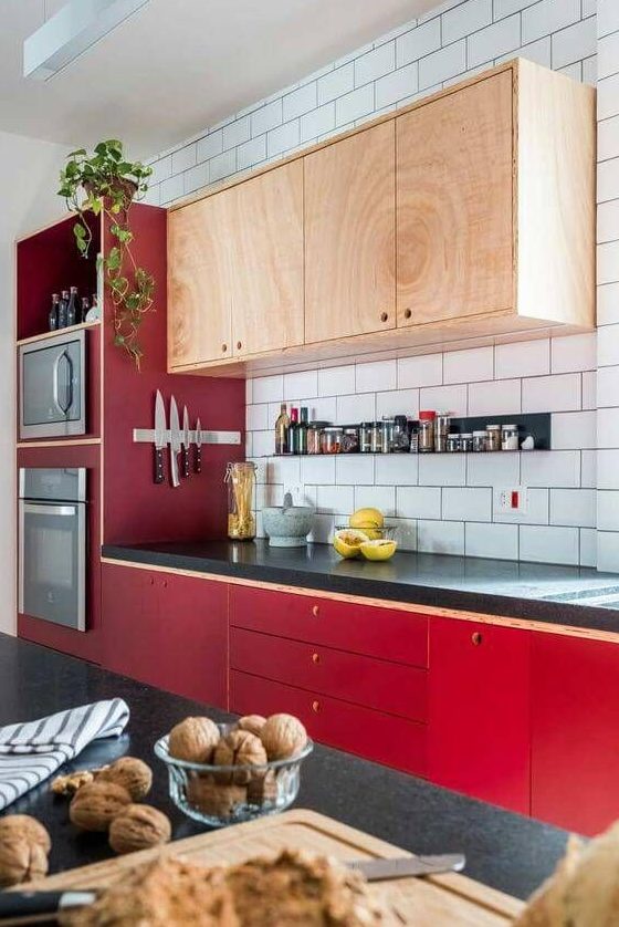 A bold mid century modern kitchen with bright red lower cabinets and neutral upper ones plus a white tile backsplash