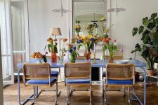 a bright dining room with molding and chevron flooring, a bold blue table and chairs, pendant lamps and colorful blooms