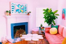 a bright dopamine decor living room with a fireplace clad with blue tile, a peachy pink sofa, bright pillows, a coffee table, a navy chair