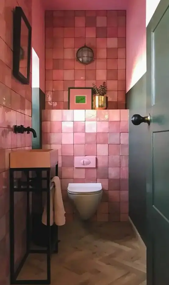 A bright mudroom with pink zellige tiles, a free standing pink sink, artworks and a plant in a gilded pot