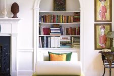a built-in arched bookcase, a green daybed with pillows, artwork and a side table with a lamp as a reading nook